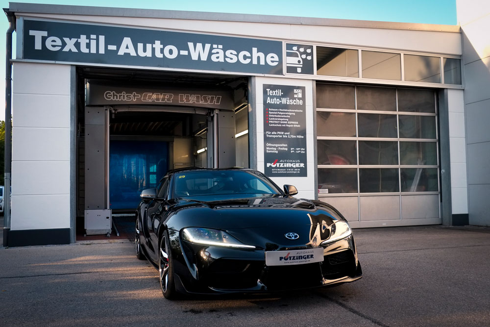 Bild zeigt einen schwarzen Toyota vor einer Textil Waschanlage